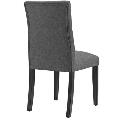 Grey fabric upholstered dining chair with tall padded back and dark wood tapered legs.