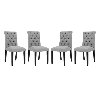 Four gray tufted fabric dining chairs with dark wood legs.