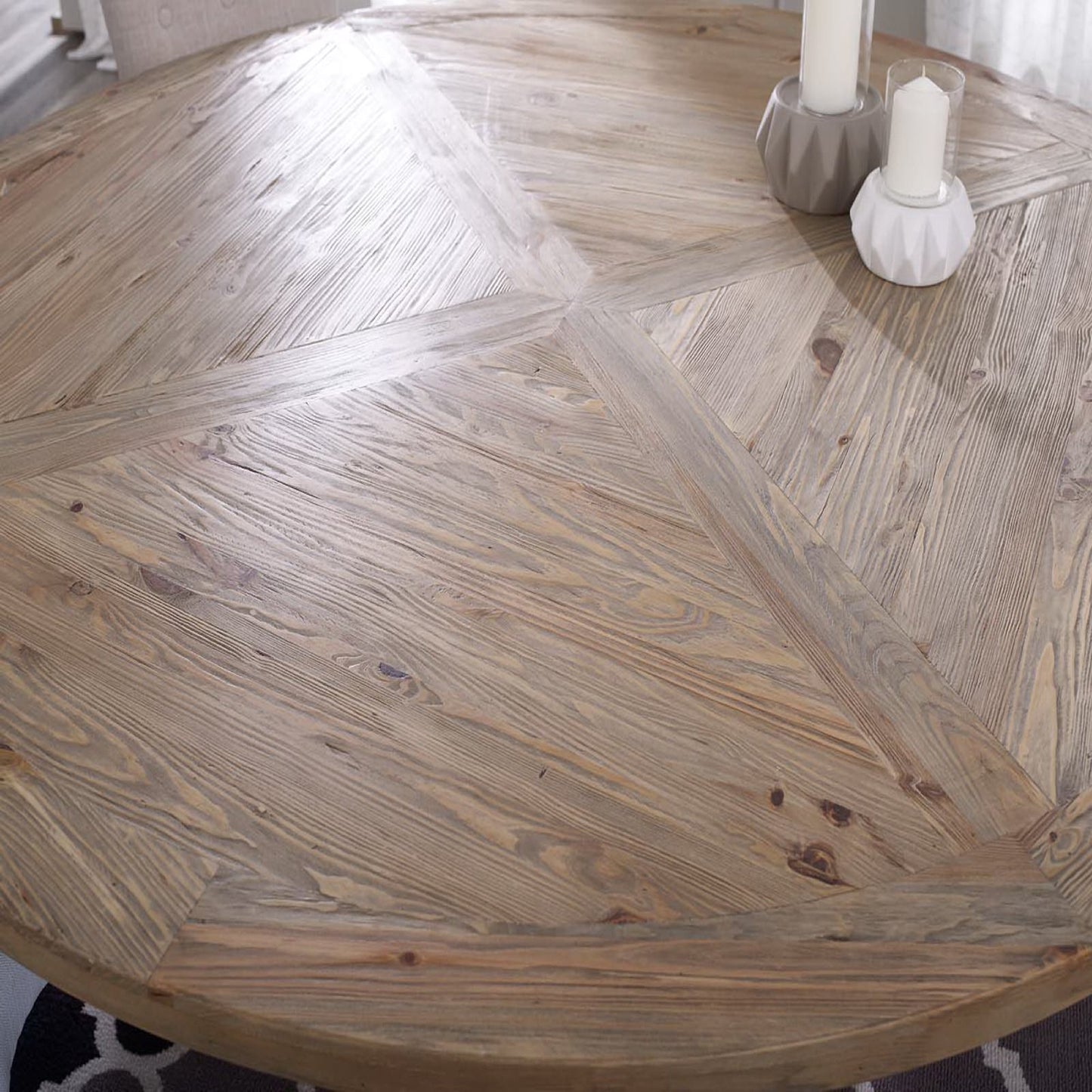 Round pine wood dining table with parquet top; candles in modern ceramic holders on surface.