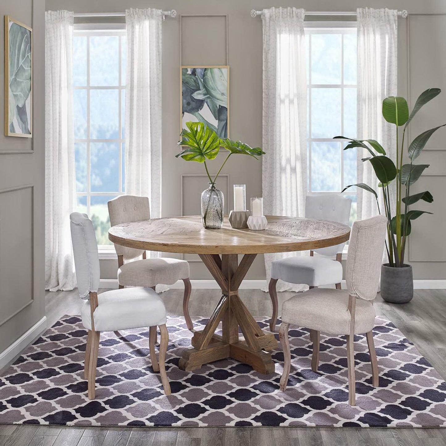 Round wooden dining table with pedestal base, beige upholstered chairs, neutral room with sheer curtains and plants; purple lattice rug.