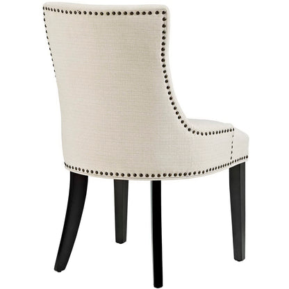 Beige linen upholstered dining chair with nailhead trim along edges, curved back, and dark wood legs.