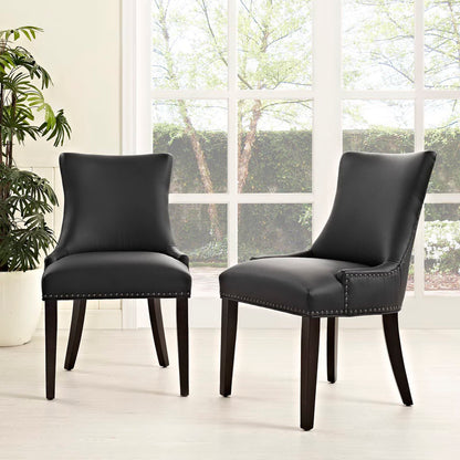 Two black faux-leather dining chairs with nailhead trim and dark wood legs in a bright room.
