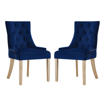 Pair of navy velvet tufted dining chairs with nailhead trim and light wood legs.