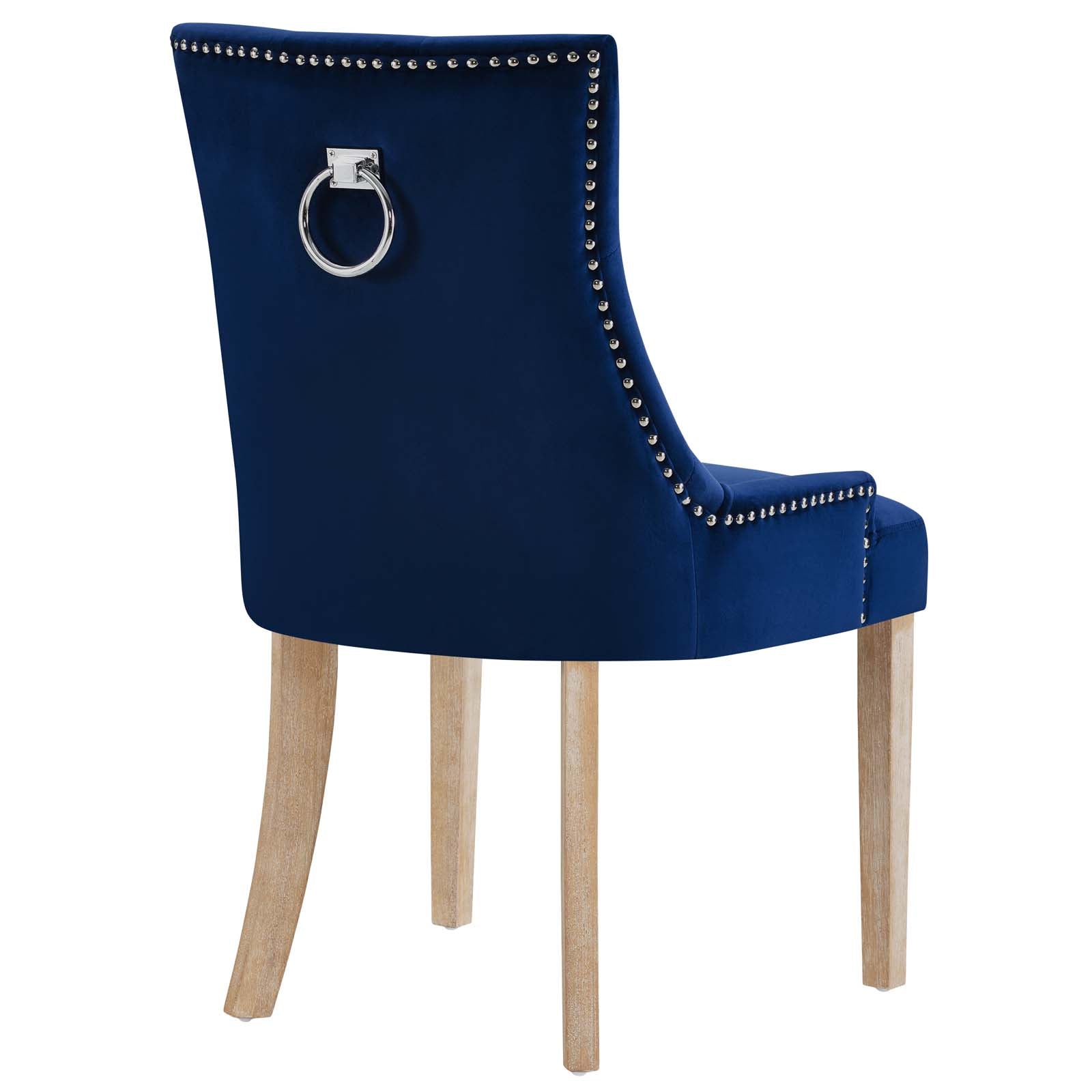 Navy blue velvet dining chair with nailhead trim and a silver ring pull on the back, light wood legs.
