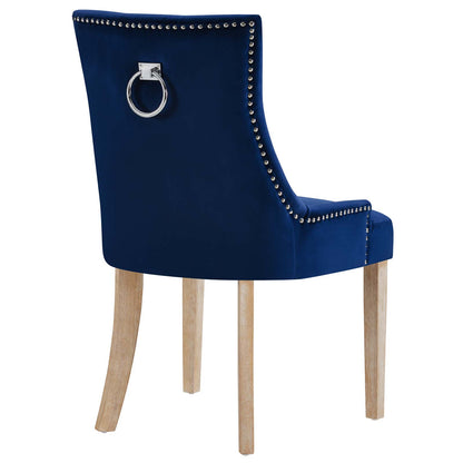 Navy blue velvet dining chair with nailhead trim and a silver ring pull on the back, light wood legs.