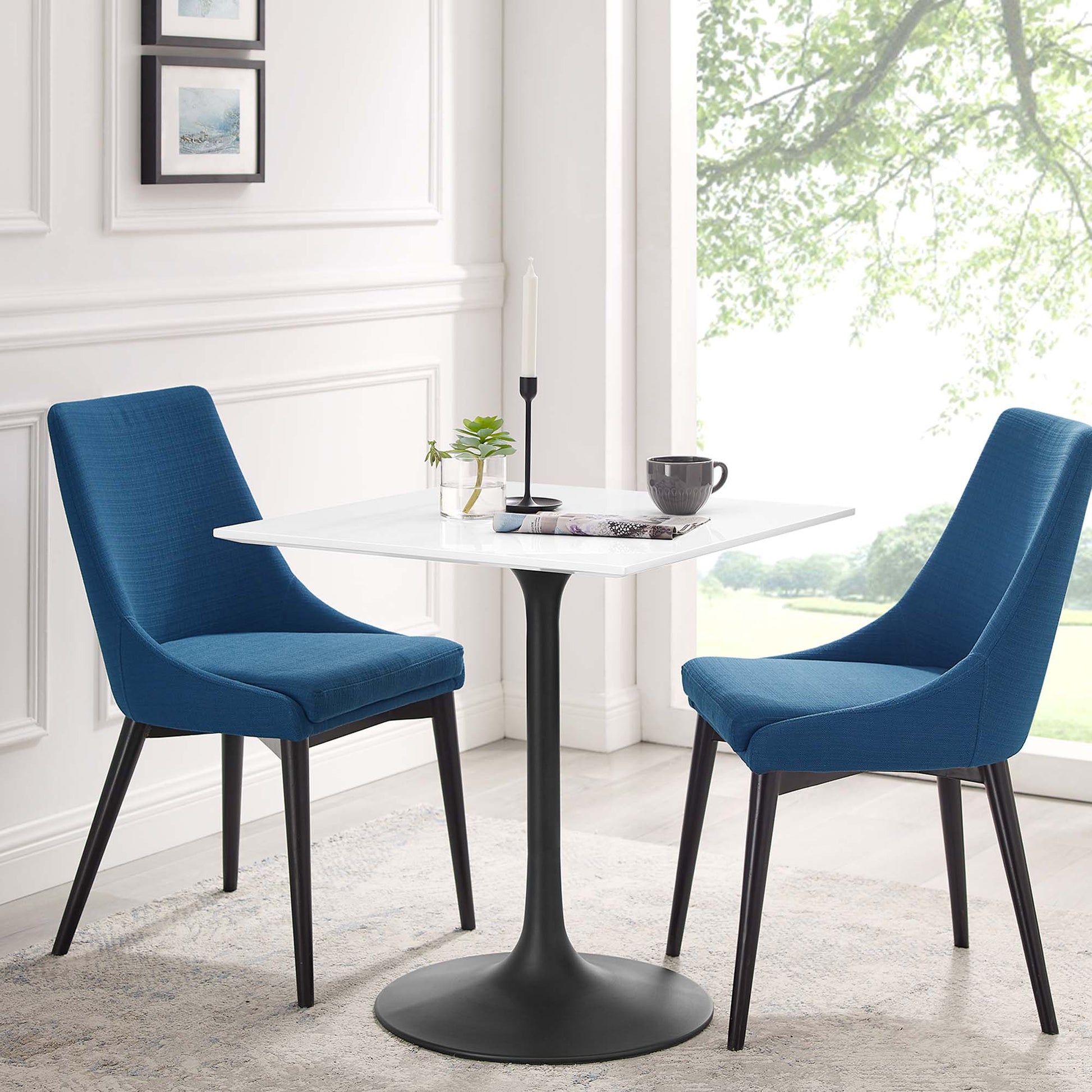 Blue fabric chairs with black legs surround a white square wood dining table in a bright modern dining nook.
