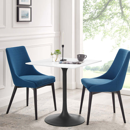 Blue fabric chairs with black legs surround a white square wood dining table in a bright modern dining nook.