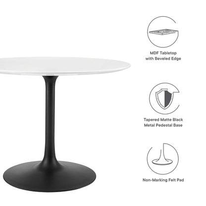 Round white wood dining table with beveled edge atop a tapered matte black metal pedestal base and non-marking felt pads.
