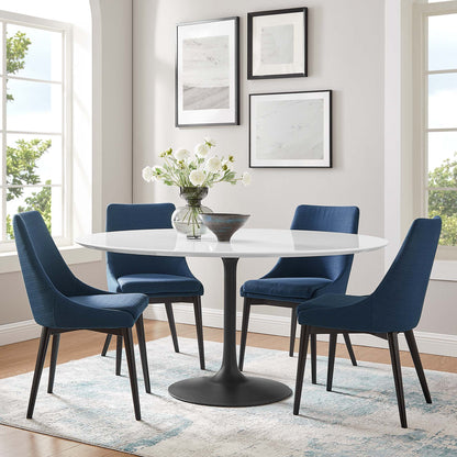 Round white pedestal dining table with four navy blue upholstered chairs, black base, vase of flowers, wall art.