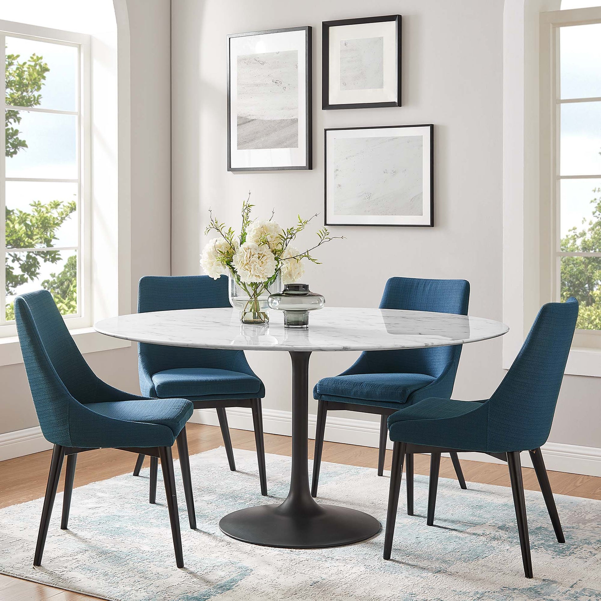 Round faux marble dining table with white pedestal base, surrounded by four teal-blue upholstered mid-century chairs.