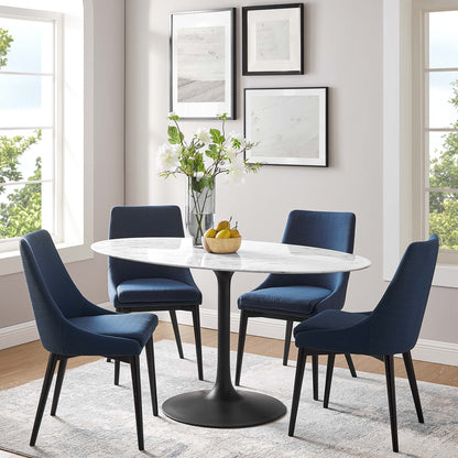 Oval faux marble dining table with pedestal base in white, in a modern dining room.