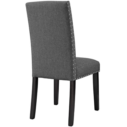 Grey upholstered dining chair with tall back, dark wood legs, and silver nailhead trim along edges.