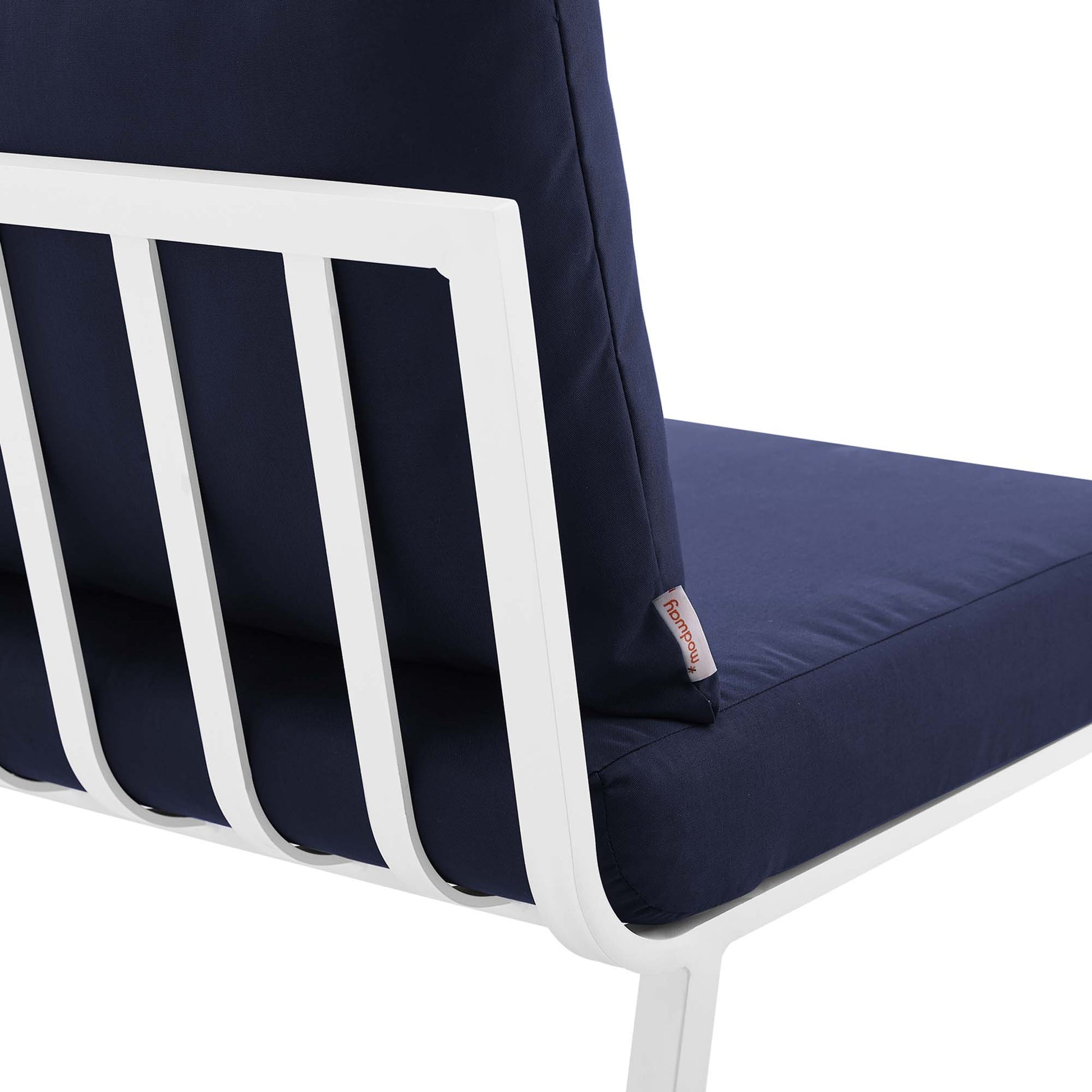 Navy cushions on a white outdoor aluminum armless chair with a slatted back.