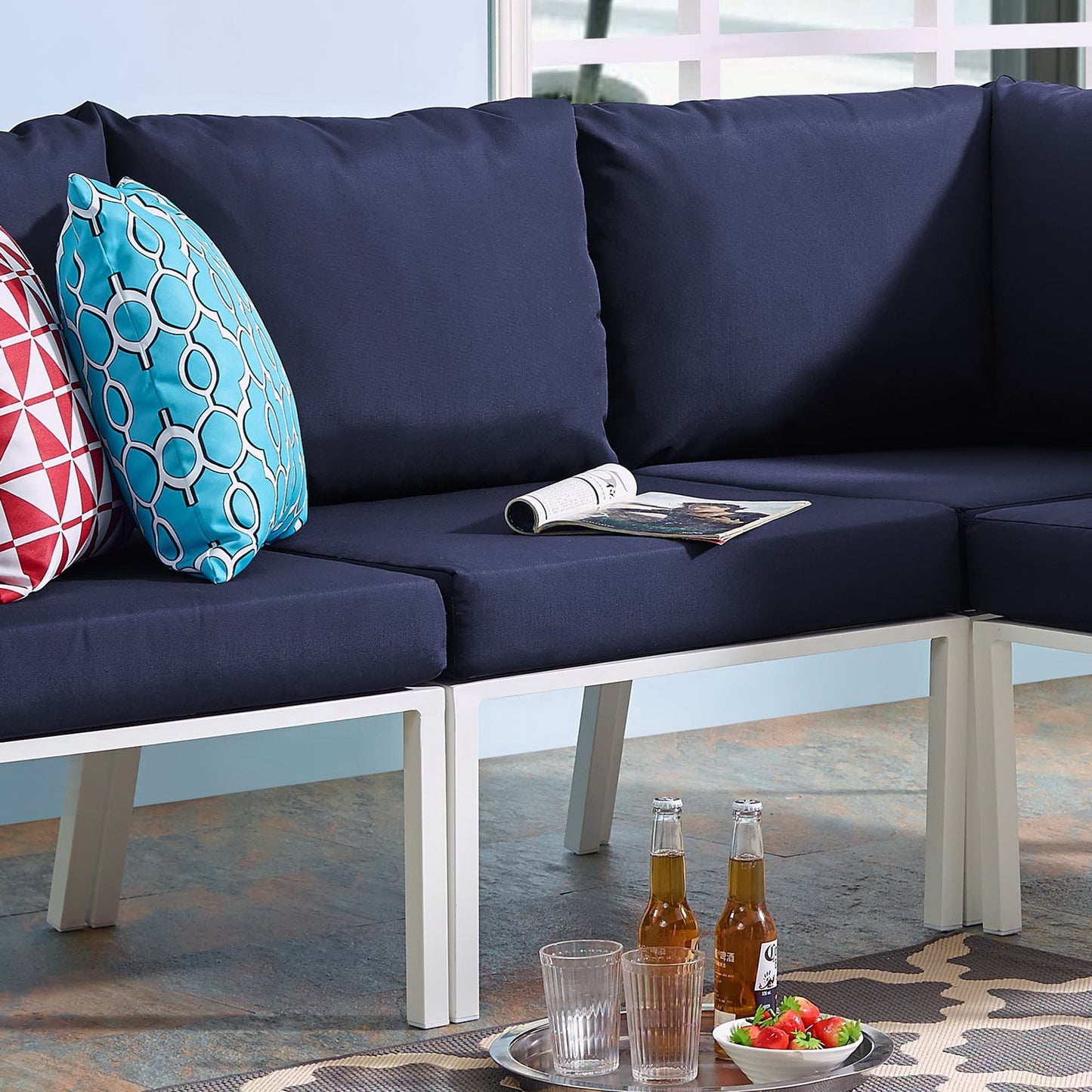 Navy outdoor patio armless chair with white aluminum frame and thick cushion, drinks on a rug.