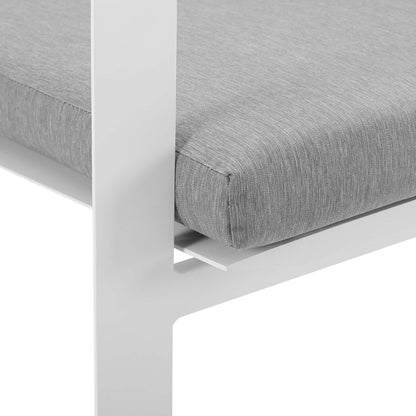 White aluminum stackable outdoor dining armchair with a light gray cushion; close-up of the leg and seat edge.