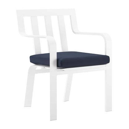 White outdoor patio aluminum dining armchair with navy seat cushion, slatted back, and curved armrests.