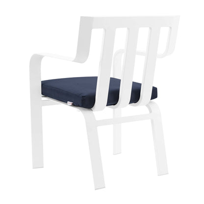 White modern armchair with slatted back, curved arms and a navy seat cushion.
