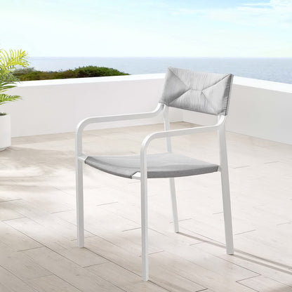 White outdoor armchair with gray seat cushion and gray back pillow on a terrace with ocean view.