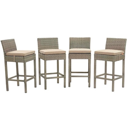 Four gray wicker bar stools with beige cushions, square legs and footrests.