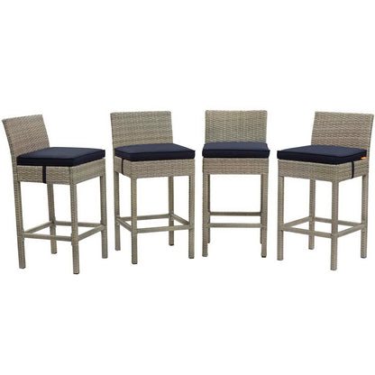 Set of four gray wicker bar stools with navy cushions, straight backrests and built-in footrests.