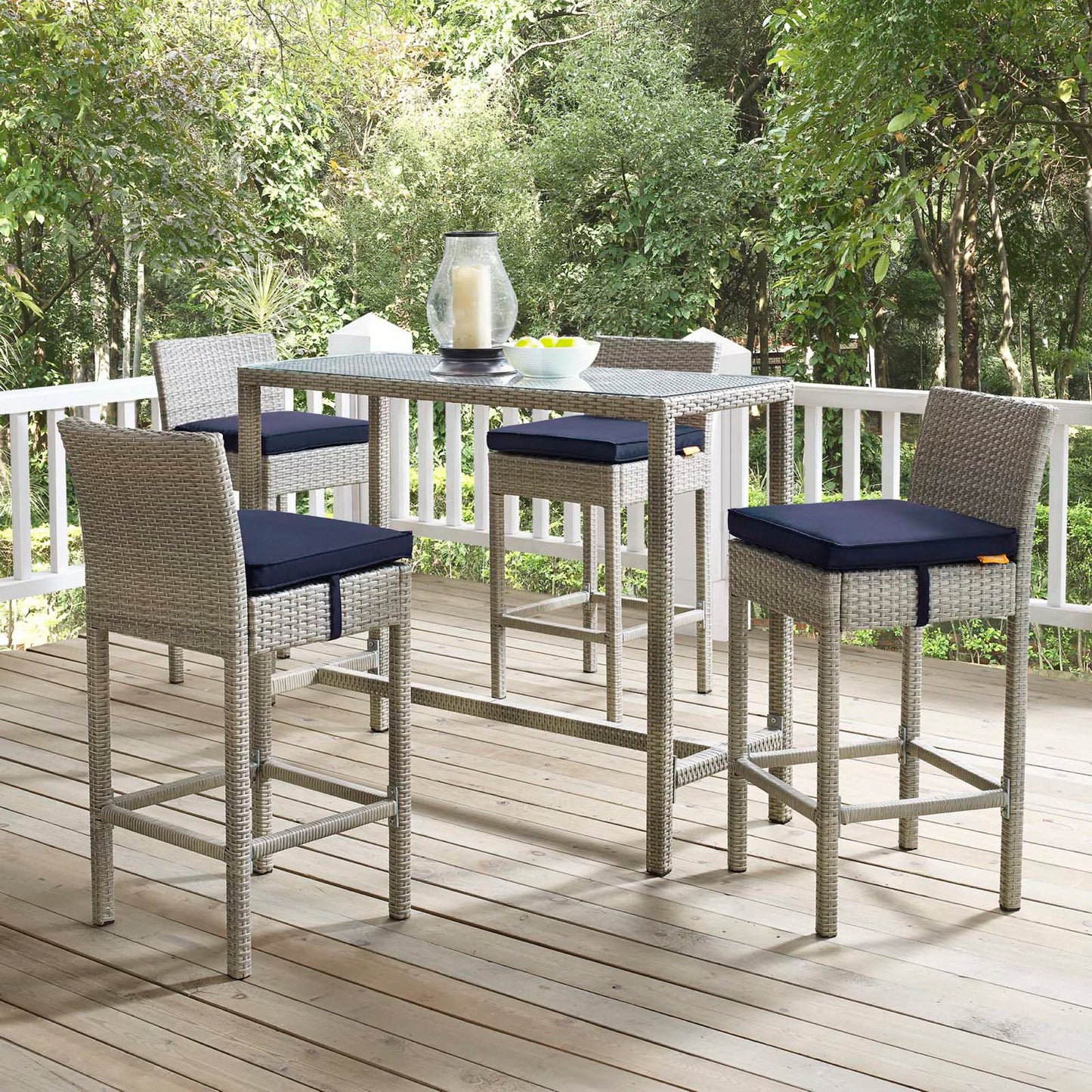 Light gray wicker outdoor bar-height stools with navy cushions, 4-piece set on a wooden deck.