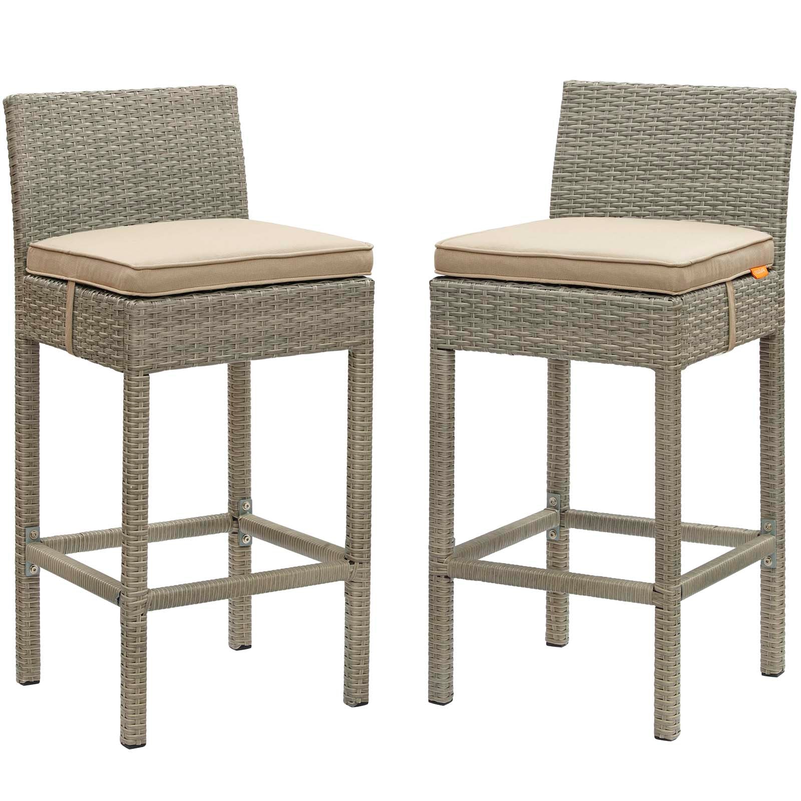 Pair of gray woven wicker outdoor bar stools with beige cushions, square legs and built-in footrests.