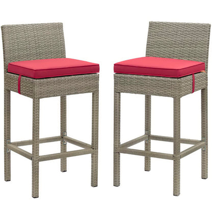 Pair of gray-wicker bar stools with red cushions, high backs, square seats, footrests, outdoor patio furniture.