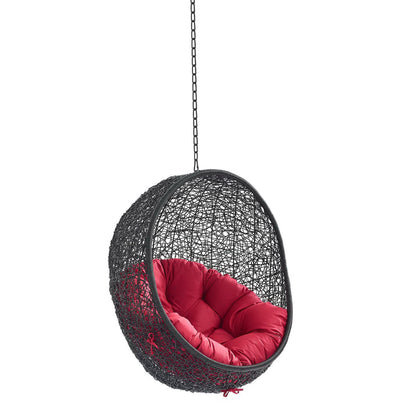Dark woven egg chair in black with red cushioned interior, hanging by chain.