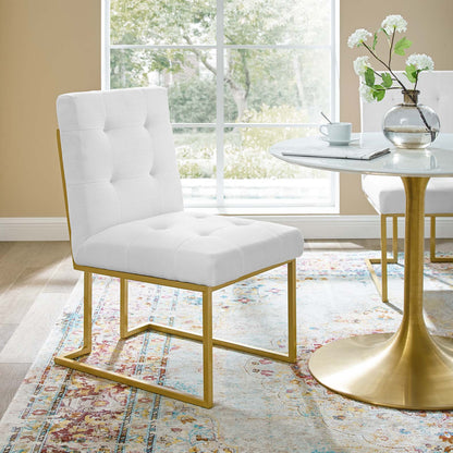 White tufted dining chair with a gold stainless steel frame beside a round marble-top table in a sunlit modern dining nook.