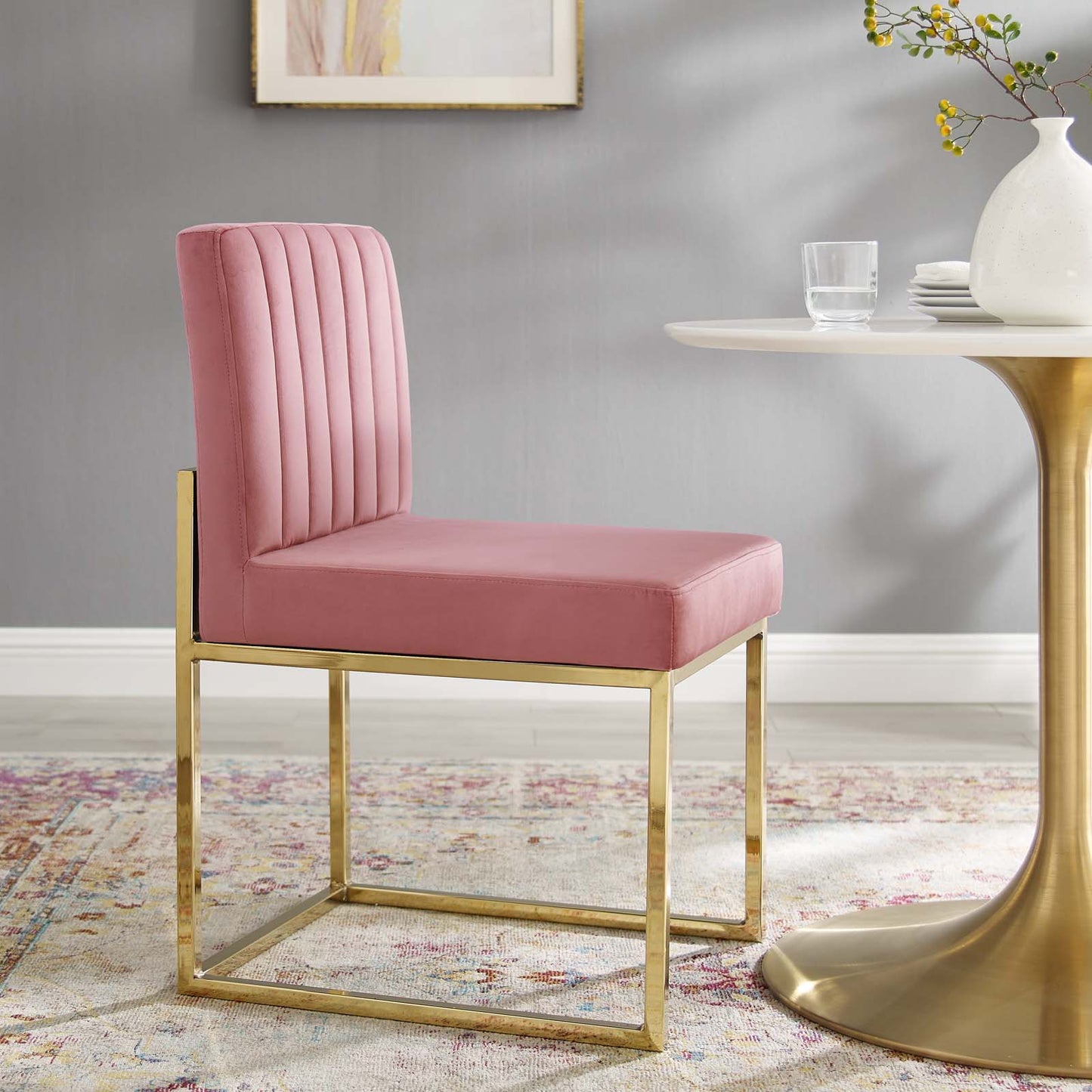 Pink velvet dining chair with a gold metal sled base, vertical channel-tufted back, contemporary glam style.