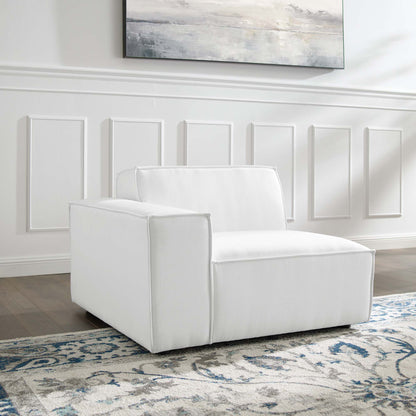 White upholstered modern armchair with boxy arms and low back, on a blue and white patterned rug in a bright paneled room.