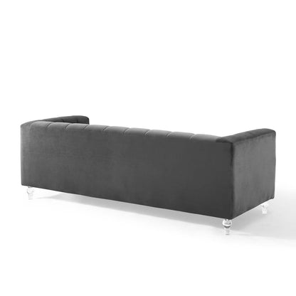Charcoal velvet sofa with tufted back, long rectangular profile and clear acrylic legs.