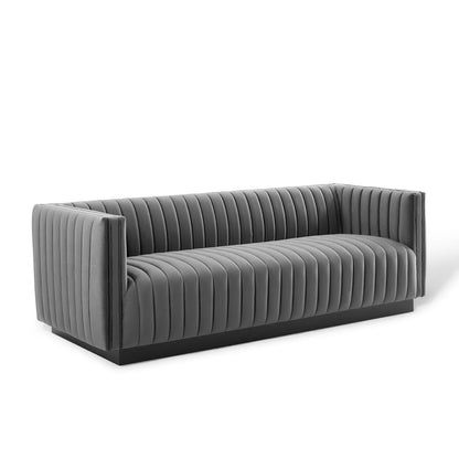 Grey velvet tufted sofa with vertical channel seams, low-profile arms, and a black base.