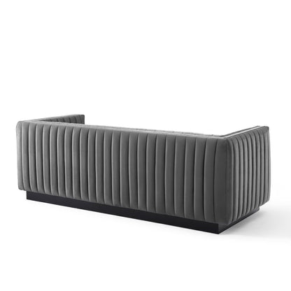 Grey channel-tufted velvet sofa with vertical ridges and a black plinth base, modern lounge piece.