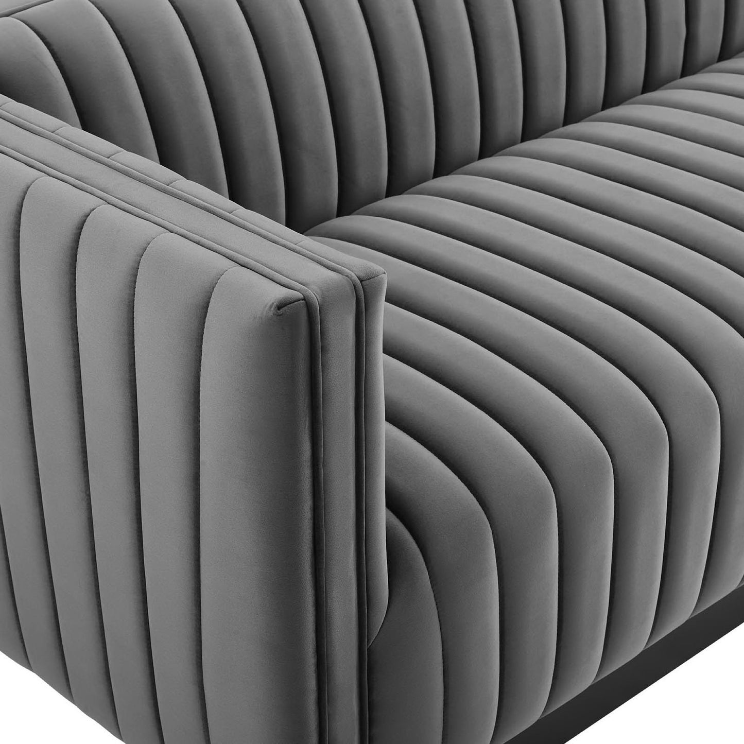 Gray velvet sofa with vertical channel tufting, modern mid-century style, plush cushions.