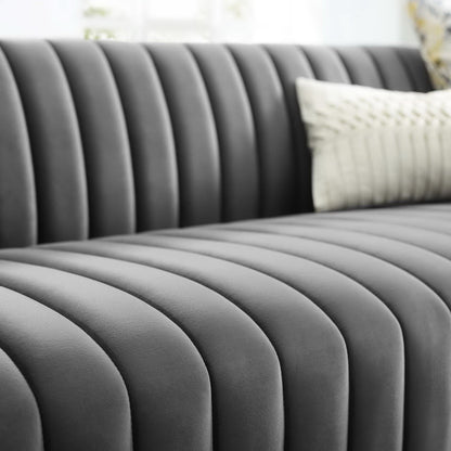 Grey velvet sofa with vertical channel tufting and a white textured pillow.