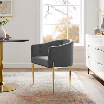 Gray tufted accent chair with curved back and gold metal legs in a bright modern living room.