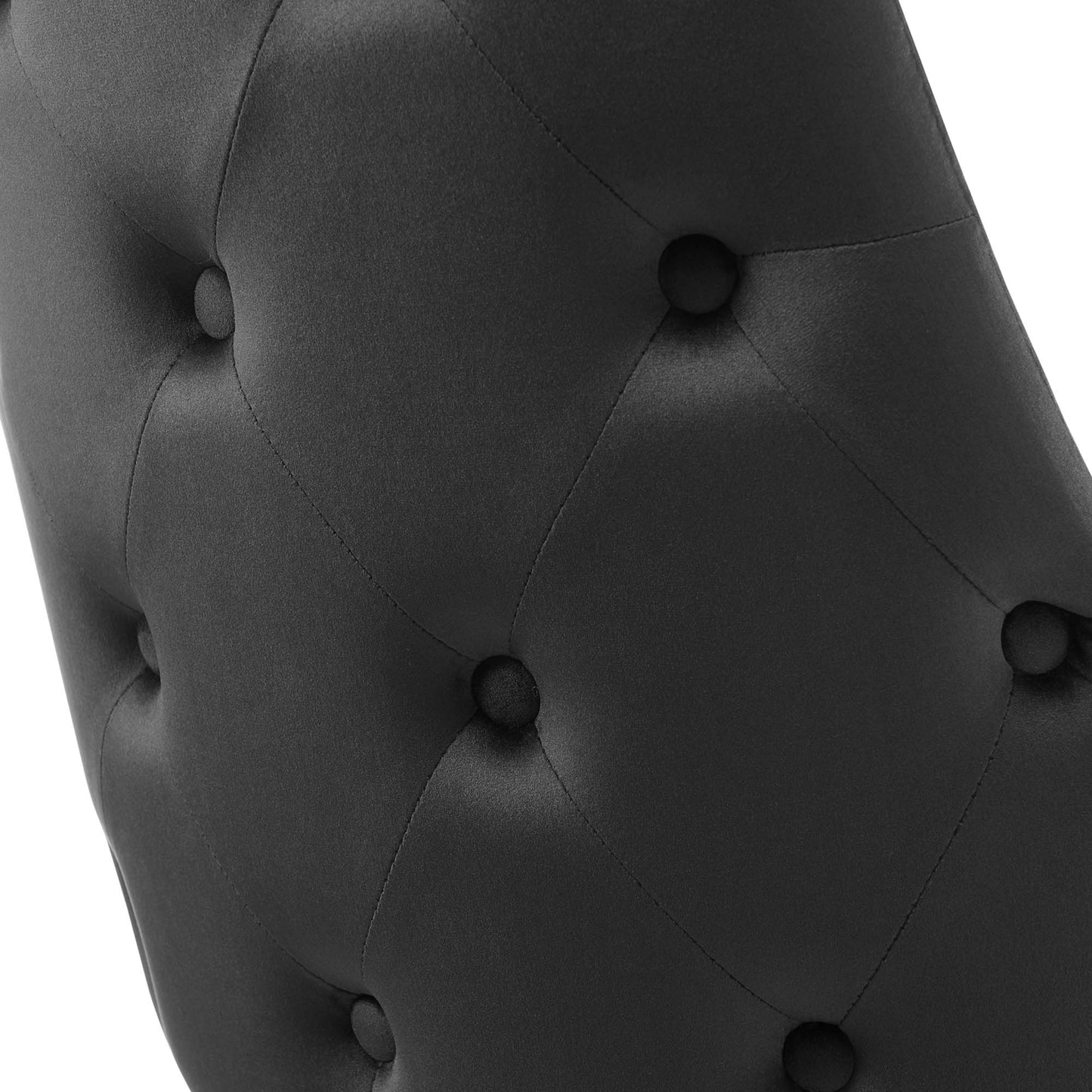Close-up of black tufted upholstery with diamond pattern and fabric-covered buttons.