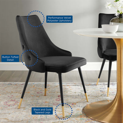 Black velvet dining chairs with button tufting and gold-tipped tapered legs, shown around a round white pedestal table.