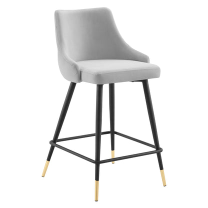 Gray upholstered counter stool with curved back, black metal legs, brass-tipped feet, and square footrest.