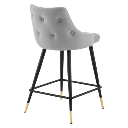 Grey tufted counter stool with curved back, black metal legs, gold-tone foot caps, and square footrest.