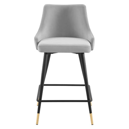 Gray upholstered counter stool with curved back, black metal legs, gold-tipped feet and a footrest.