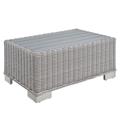 Rectangular gray wicker coffee table with glass top and short square metal legs.