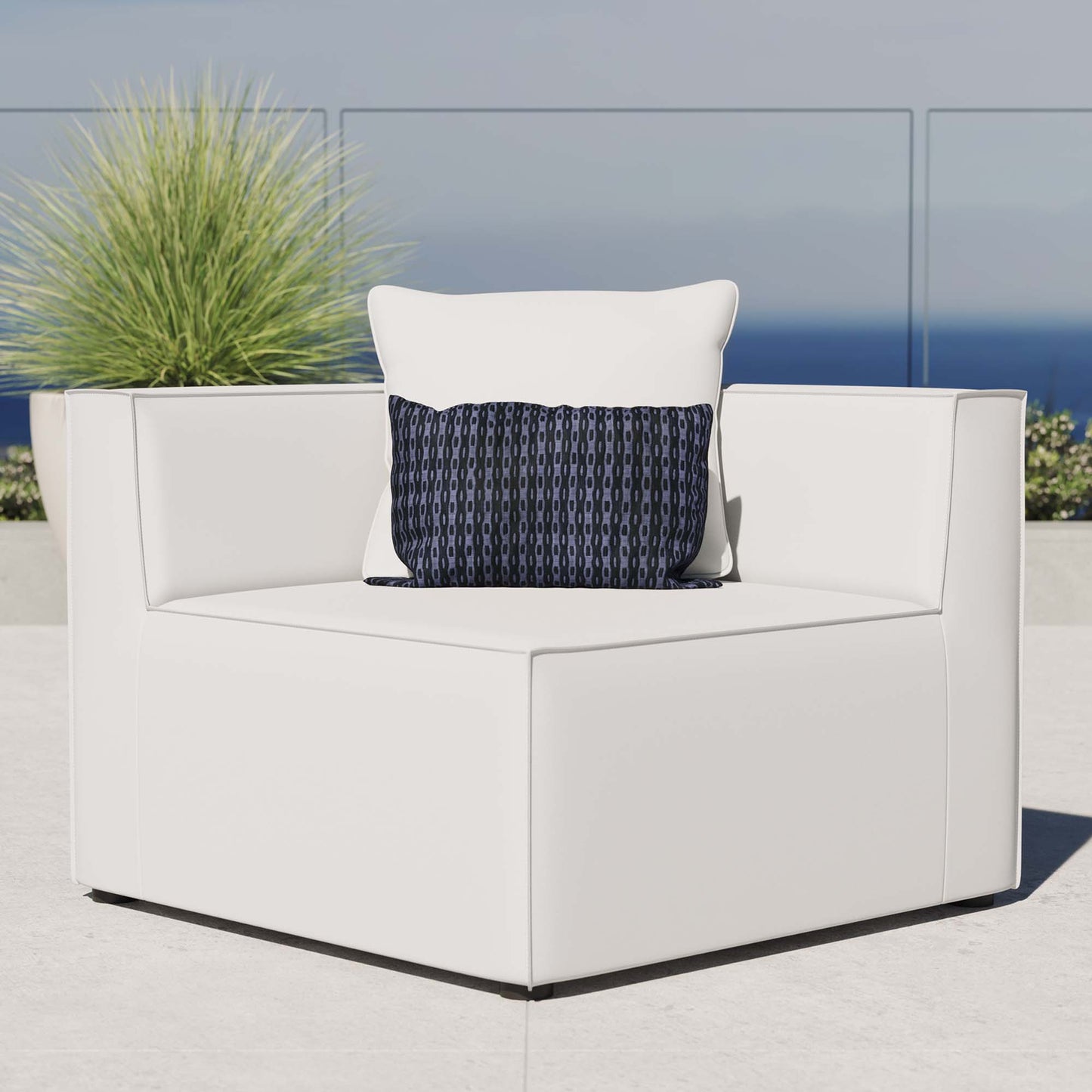 White outdoor modular sectional sofa corner chair with square arms & thick cushions, accented by a navy geometric throw pillow.