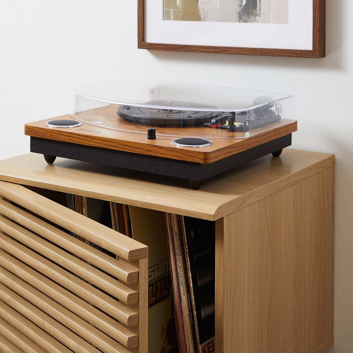 Oak finish vinyl record display stand with a slatted door, LPs inside, and a clear dust cover on top.