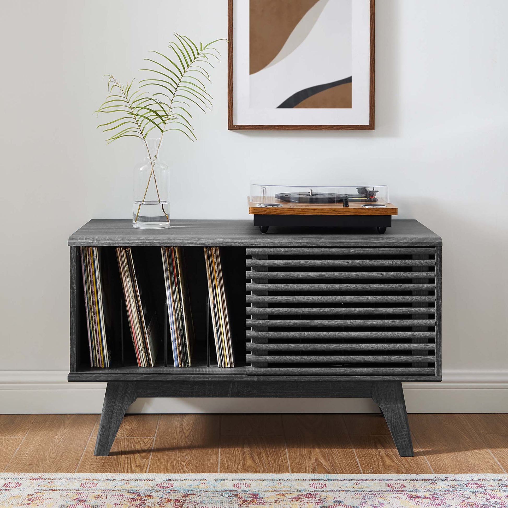 Brown render vinyl record display stand with vinyl records in left slots, slatted right door, turntable on top, vase of palm fronds.