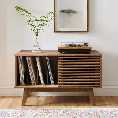 Brown wooden vinyl record display stand with vinyl records, a turntable, and a vase of greenery.