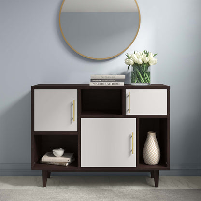 Display stand in cappuccino white finish with dark wood tones, white panel doors with gold pulls, open shelves; gold-framed mirror, vase and books on top.