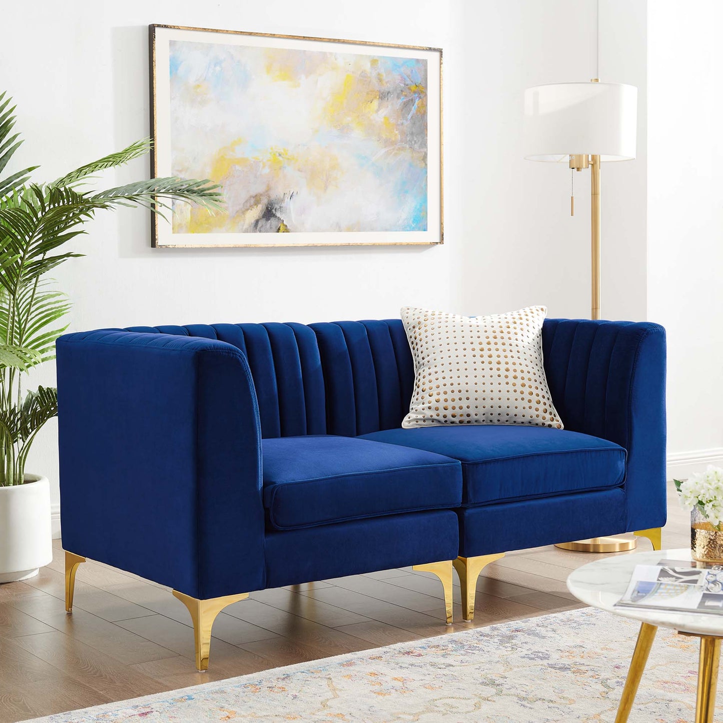 Navy blue velvet loveseat with vertical channel tufting & gold metal legs in a bright modern living room.