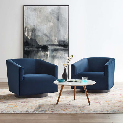 Two navy blue velvet swivel chairs with wooden bases surround a white round coffee table; abstract art, vase, patterned rug.